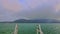 Camera on Boat Speeds across Azure Sea along Rope-way