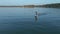 Camera flies around a man riding on a hydrofoil surfboard on large blue lake