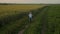 The camera flies low behind a boy who is riding a bike fast at sunset