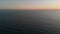 Camera flies over the blur ocean waves to the clean horizon. The camera flies forward over the sea into the sunset