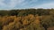 The camera flies up to the autumn forest and rises high above it.