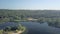 Camera is flying over amazing calm river and coast with forest and high trees