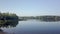 Camera is flying over small beach between trees in sunny calm weather in morning