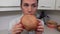 Camera focuses on the burger then on the woman who is starting to eat