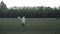 The camera focuses on the raindrops on the blurred background of the footballer in a raincoat with the ball on the field