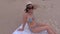 Camera focusing on flip flops and woman in straw hat on beach