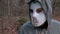 Camera focusing on machete then on man in scary Halloween mask