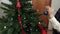 Camera follow hand with Christmas decoration near Christmas tree