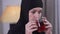 Camera following cup of tea in female hands. Charming serious Muslim woman in traditional hijab drinking hot drink at