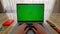 Camera following woman's hands. POV view of woman working on a laptop with a green screen. Bright light window on a