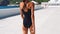 Camera follows Beautiful confident shapely woman in black swimwear