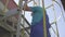 Camera follows steps of factory worker climbing up the ladder outdoors on sunny day. Adult professional Caucasian man in