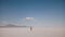 Camera follows tired exhausted young man lost alone walking at dangerous epic hot sunny salt desert lake in Utah USA.