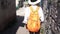 Camera follows woman tourist in white shirt and straw hat walking on ancient narrow street