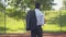 Camera follows young African American businessman entering outdoor basketball court. Back view of confident man in