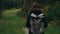 Camera follows young girl hiker walking outdoors on background of forest landscape with tall trees in mountains.