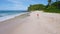 Camera follows young woman as she walks on the paradise Anse Bazarca beach. Aerial 4k footage view of tanned girl on