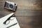 Camera, glasses and notepad on wooden background