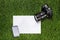 Camera with mobile phone and sheet of paper on the grass