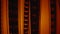 Camera movement over old film negatives in red light. Retro tape filmstrip with picture, close up. Analog old strips of