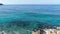 Camera moves forward from rocky coast along turquoise blue waves rolling in sunshine. Seascape of magnificent Cyprus