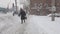 The camera moves over snow-covered sidewalk in a city on a dark, cloudy day.