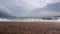 Camera moves slowly along sandy beach with trash, and imprints of animal tracks