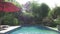 The camera moves on a tropical garden with the pool lengthways the blossoming trees. Bali. Indonesia.