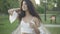 Camera moves up along slim charming Middle Eastern woman in white dress and straw hat strolling outdoors with picnic