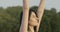 Camera moves up following movement of young Caucasian ballerina raising hands up in morning sunrays. Side view close-up