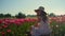 Camera moving along road in red tulips field with girl in hat sitting in flowers