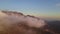 Camera moving through clouds in mountains. Fantastic dreamy sunrise on top of rocky mountain with view into misty valley