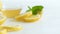 Camera panning along lemons, leaves of mint and jar with bee honey on white wooden table