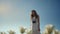 Camera rotation around young woman enjoying white flowers on blue sky background