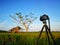 Camera setting at tripod to take photo or video of sunrise or sunset moment. Blurred sea in background.