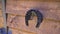 Camera slide on. Close-up on a iron metal horseshoe hanging on a hay on the wooden pallet wall. Good luck symbol, horse
