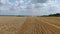 Camera span of a massive wheat field with heavy machinery at work