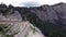 Camera tracking of a red car in motion, aerial view of winding road surrounded by mountains, beautiful roads for traveling by moto