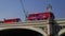 Camera tracks red London bus crossing Westminster Bridge