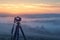 Camera on tripod captures foggy summer morning, evoking serene solitude