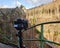 Camera on a tripod films a rock scenery behind a green railing