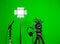 The camera on the tripod, led floodlight, headphones and a directional microphone on a green background. The chroma key
