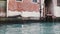 Camera zooms in on beautiful atmospheric red building on Venice canal, Italy with beautiful blue water and seagull on it