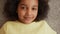Camera zooms in on face and eyes of small African American girl looking at camera and smiling. Teenager girl lies on the