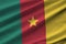 Cameroon flag with big folds waving close up under the studio light indoors. The official symbols and colors in banner