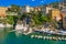 Camogli Harbor aerial view. Colorful buildings, boats and yachts moored in marina with green water