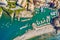 Camogli Harbor aerial view. Colorful buildings, boats and yachts moored in marina with green water