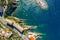 Camogli rocky coast aerial view. Boats and yachts moored near harbor with green water and lighthouse.