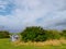 Camouflage tent in a field by a bush, blue cloudy sky, Travel and tourism concept