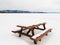 Camp table benches and snowy frozen lake landscape